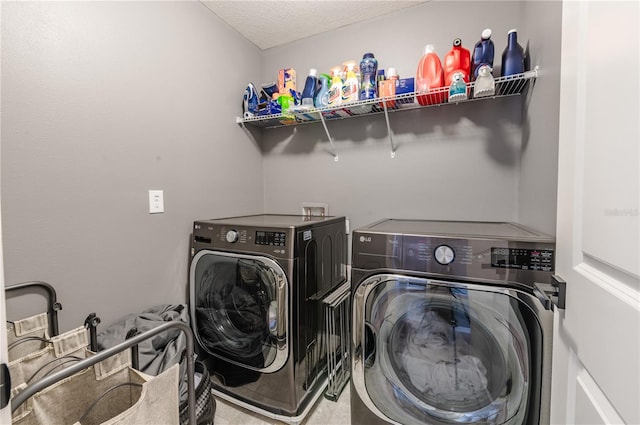 clothes washing area with washing machine and clothes dryer and a textured ceiling