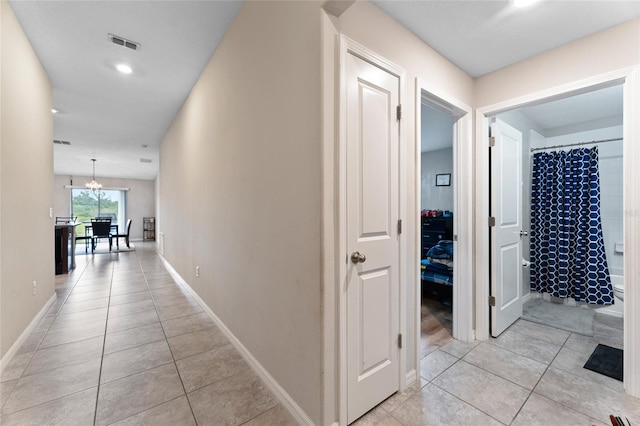 corridor featuring an inviting chandelier and light tile flooring