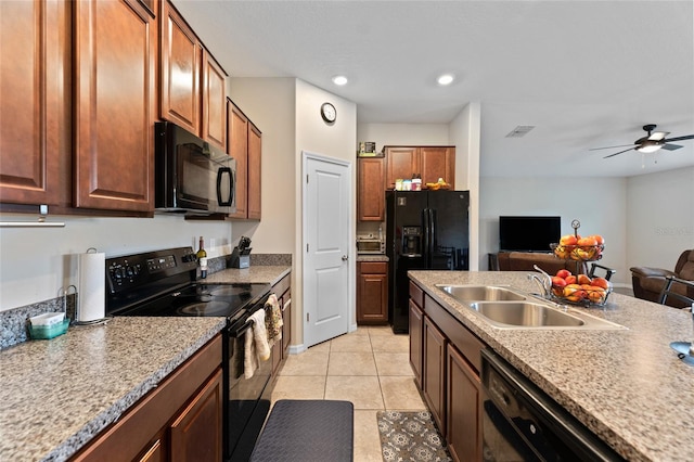 kitchen with light stone countertops, black appliances, sink, ceiling fan, and light tile floors