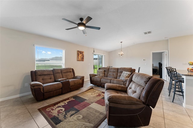 living room with vaulted ceiling, plenty of natural light, light tile flooring, and ceiling fan with notable chandelier