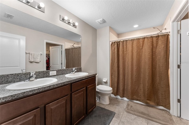 bathroom featuring dual sinks, toilet, tile floors, large vanity, and a textured ceiling