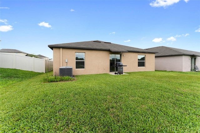 rear view of property featuring a lawn and central AC unit