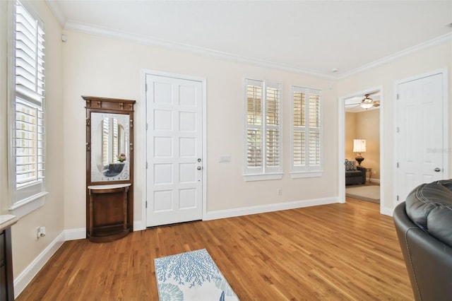 foyer entrance featuring ornamental molding, wood finished floors, a ceiling fan, and baseboards