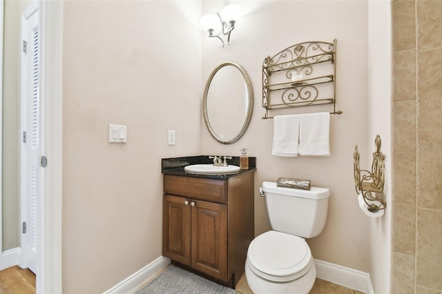 bathroom featuring toilet, vanity, and baseboards