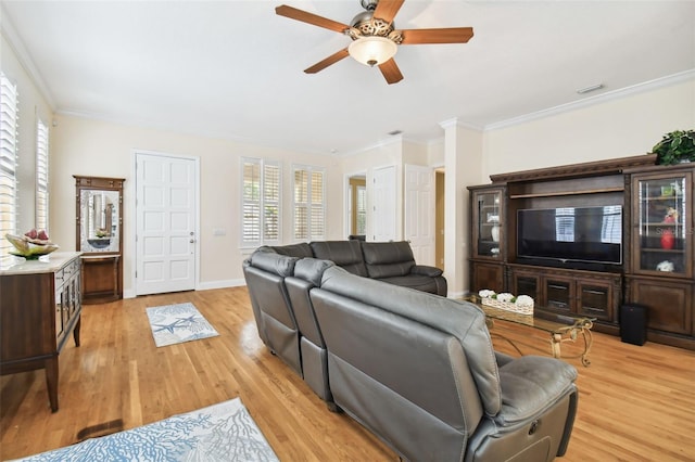 living room featuring ornamental molding, light wood-style flooring, visible vents, and baseboards