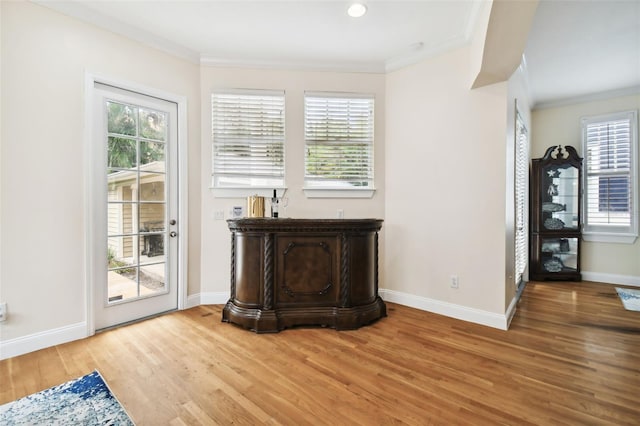 interior space featuring baseboards, light wood-style flooring, and crown molding