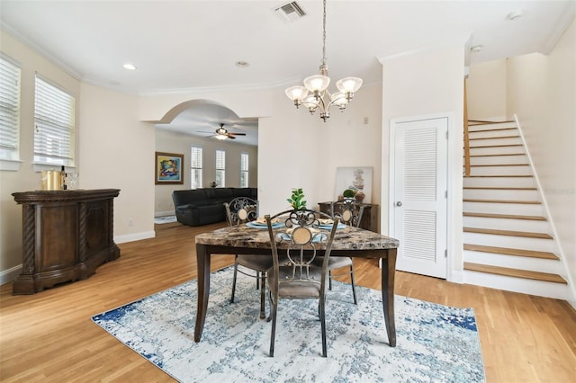 dining space with arched walkways, crown molding, visible vents, stairway, and wood finished floors