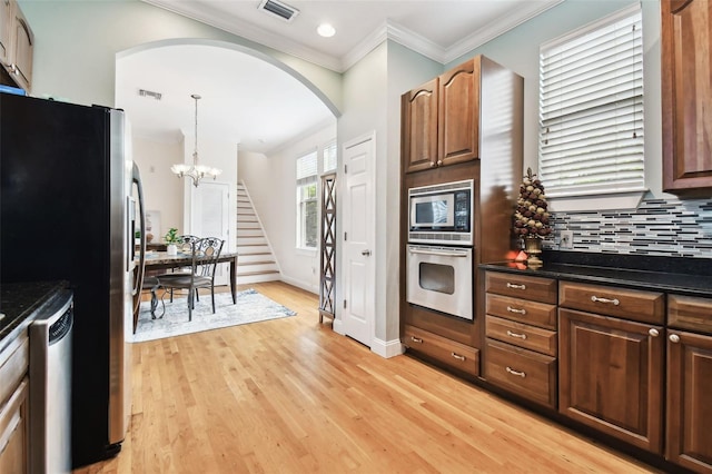 kitchen with light wood finished floors, visible vents, decorative backsplash, dark countertops, and appliances with stainless steel finishes