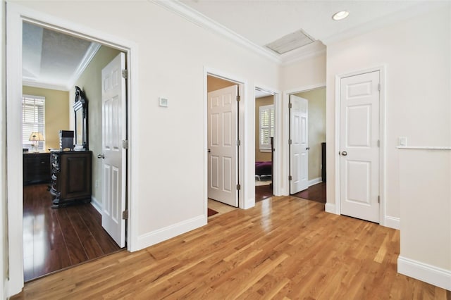 corridor with recessed lighting, baseboards, light wood finished floors, attic access, and crown molding