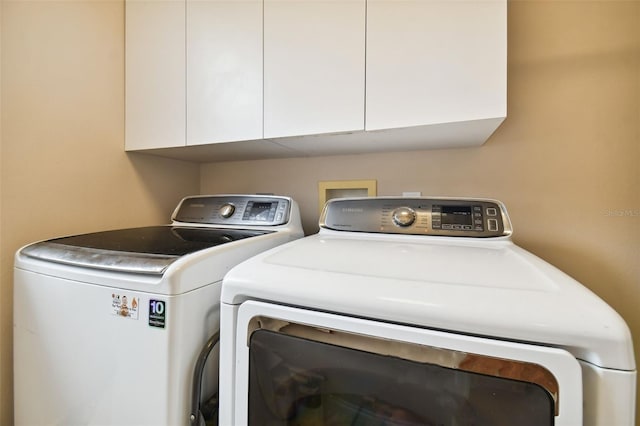 clothes washing area featuring cabinet space and washing machine and clothes dryer