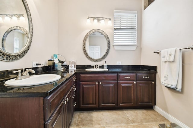 bathroom featuring double vanity, tile patterned flooring, a sink, and baseboards