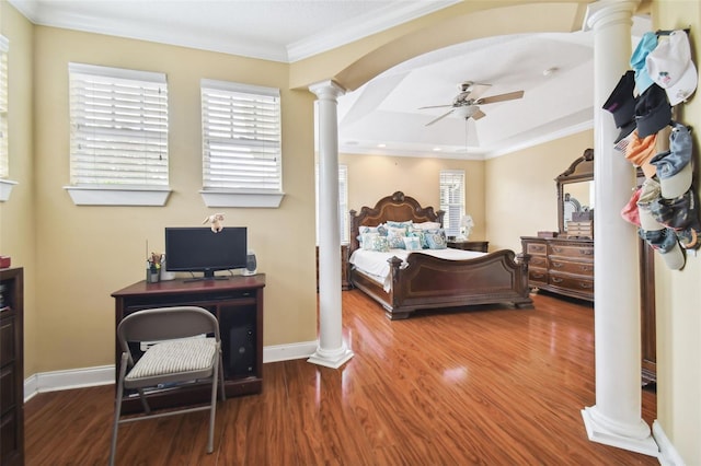 bedroom with arched walkways, crown molding, ornate columns, and wood finished floors