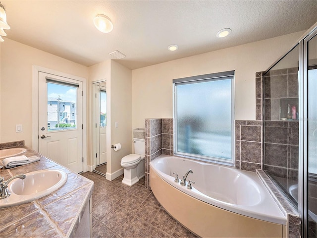 bathroom with a textured ceiling, a bathing tub, vanity, and toilet