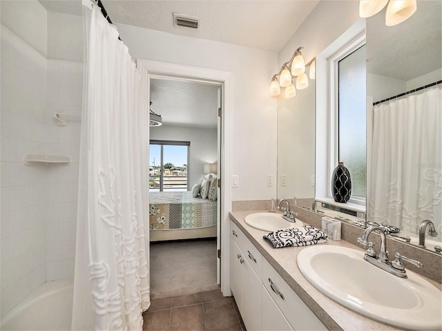 bathroom with tile patterned flooring, shower / bathtub combination with curtain, a textured ceiling, and vanity