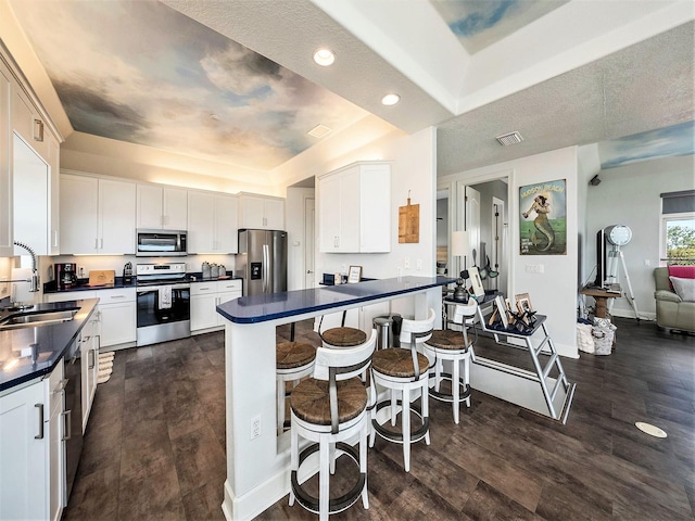 kitchen featuring stainless steel appliances, sink, white cabinets, a kitchen breakfast bar, and dark hardwood / wood-style floors