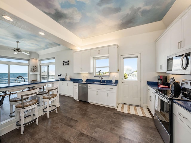 kitchen featuring appliances with stainless steel finishes, white cabinetry, a water view, and sink