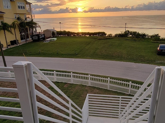 yard at dusk featuring a water view