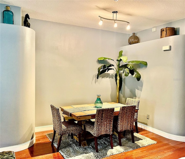 dining space with a textured ceiling and hardwood / wood-style flooring