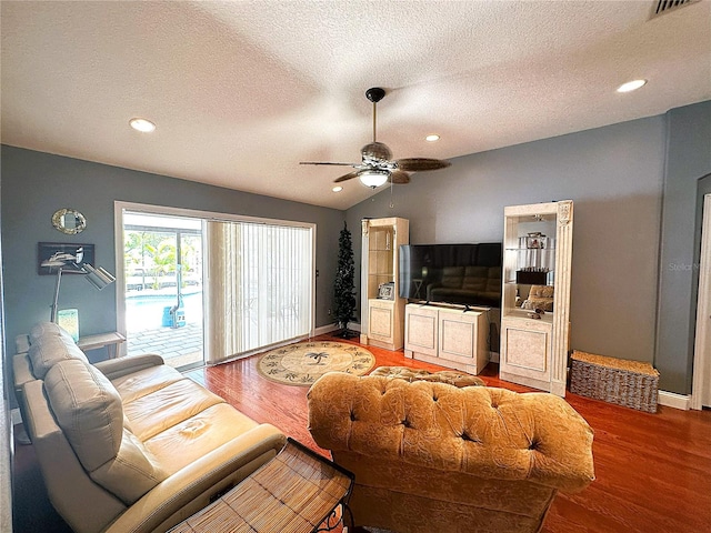 living room featuring a textured ceiling, hardwood / wood-style flooring, vaulted ceiling, and ceiling fan