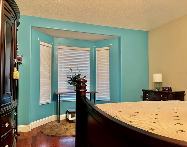 bedroom with a textured ceiling and dark hardwood / wood-style floors