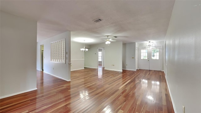 unfurnished living room with hardwood / wood-style floors, ceiling fan with notable chandelier, and a textured ceiling