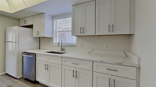 kitchen with dishwasher, light stone counters, wood finished floors, white cabinets, and a sink