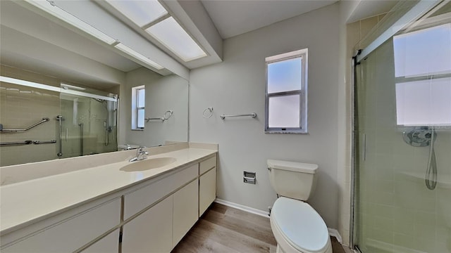 full bath featuring vanity, wood finished floors, baseboards, a stall shower, and toilet