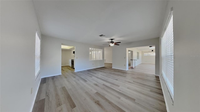 unfurnished living room featuring visible vents, baseboards, light wood-style floors, and a ceiling fan