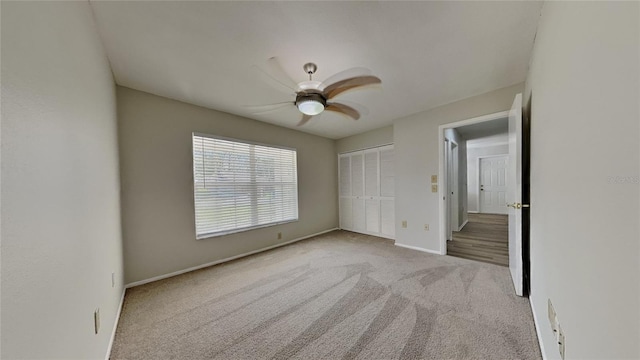 unfurnished bedroom featuring a ceiling fan, carpet, a closet, and baseboards