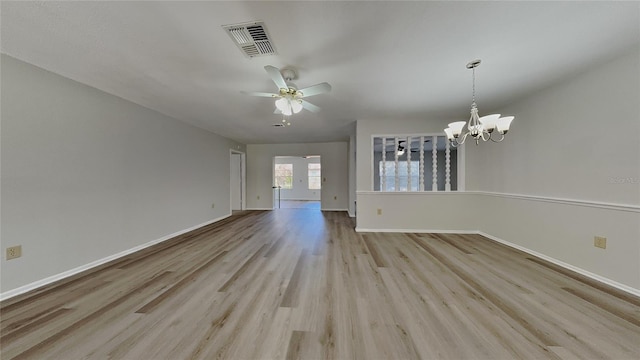 spare room with visible vents, ceiling fan with notable chandelier, light wood-type flooring, and baseboards