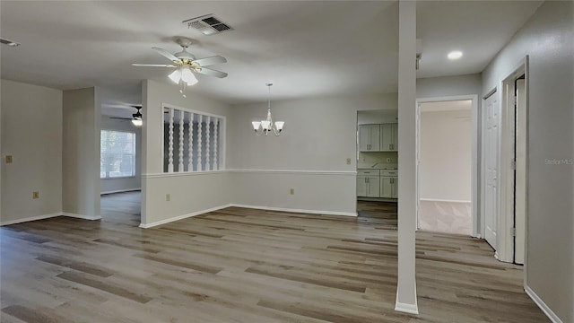 unfurnished dining area featuring visible vents, ceiling fan with notable chandelier, light wood-type flooring, and baseboards