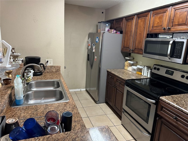 kitchen with stainless steel appliances, sink, and light tile floors