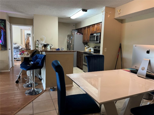 interior space featuring stainless steel appliances, a kitchen breakfast bar, a textured ceiling, and kitchen peninsula