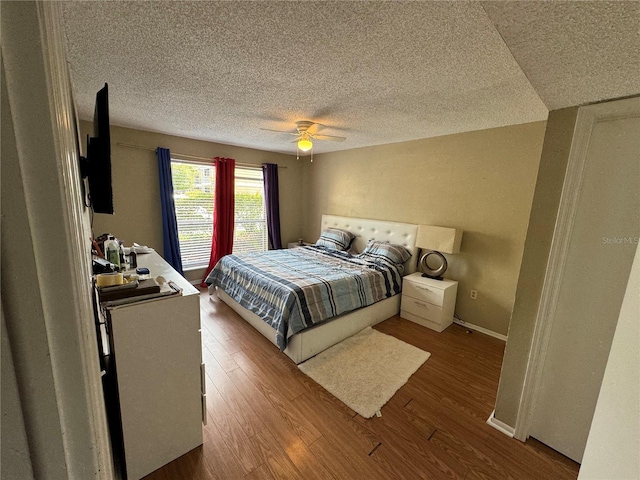 bedroom with a textured ceiling, ceiling fan, and hardwood / wood-style floors