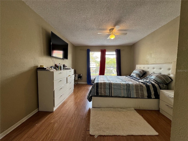 bedroom with hardwood / wood-style floors, ceiling fan, and a textured ceiling