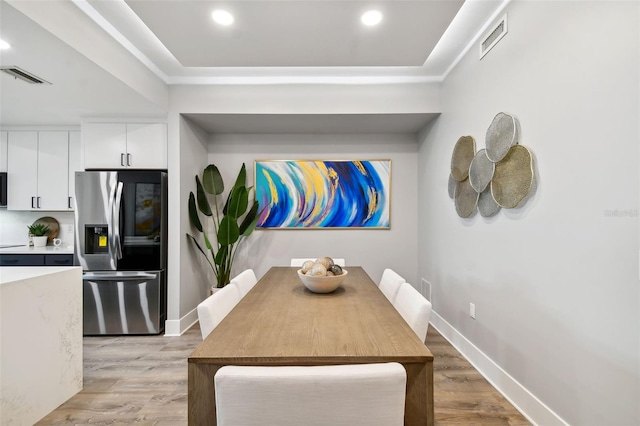 dining space with baseboards, visible vents, and light wood finished floors