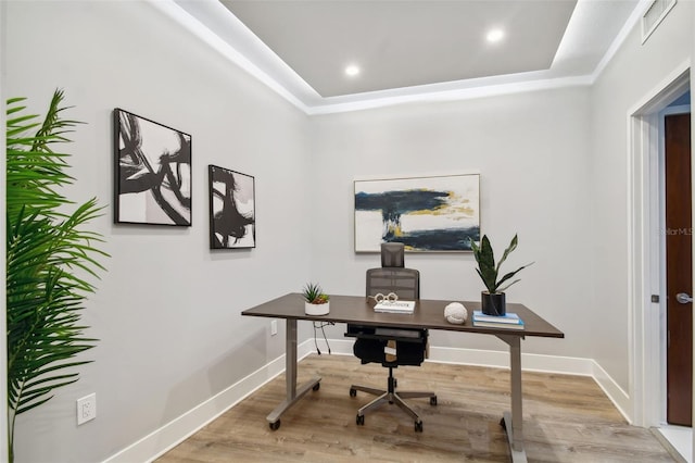 home office featuring light hardwood / wood-style floors and a tray ceiling