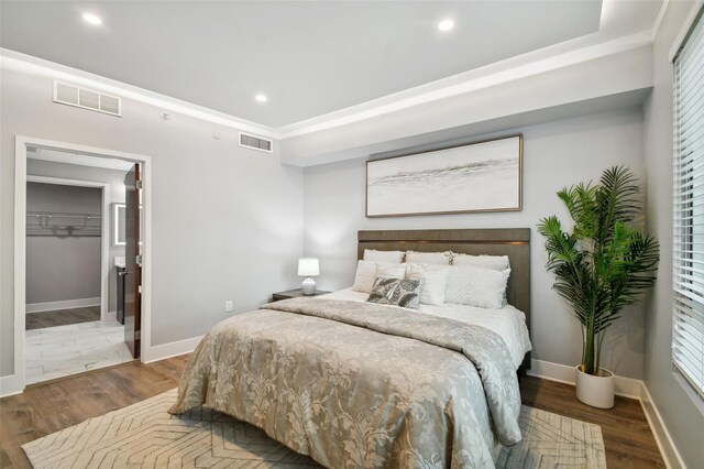 bedroom with a spacious closet and dark hardwood / wood-style flooring