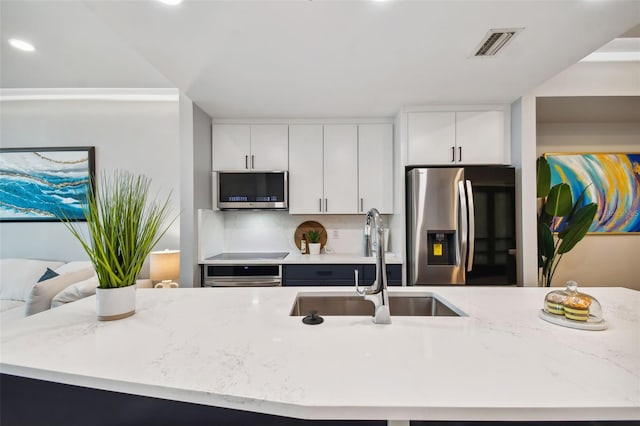 kitchen featuring appliances with stainless steel finishes, sink, light stone countertops, and white cabinets