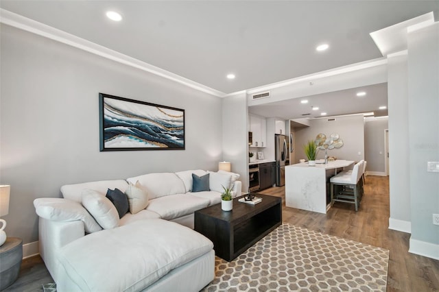 living area featuring baseboards, wood finished floors, visible vents, and recessed lighting