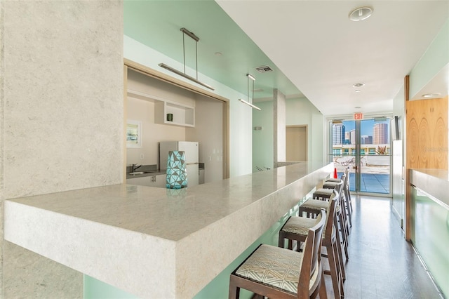 kitchen with sink, kitchen peninsula, white refrigerator, and a kitchen bar