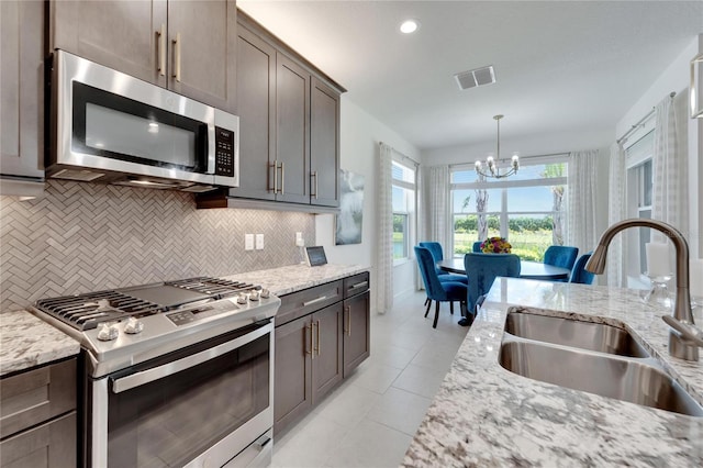 kitchen with light stone counters, sink, stainless steel appliances, and tasteful backsplash