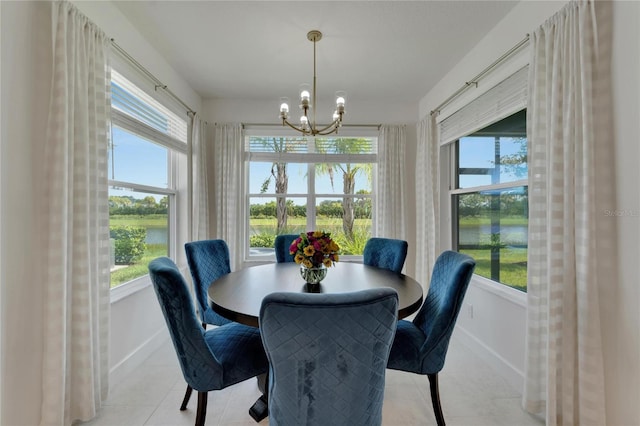 dining space featuring a water view, an inviting chandelier, plenty of natural light, and light tile patterned flooring