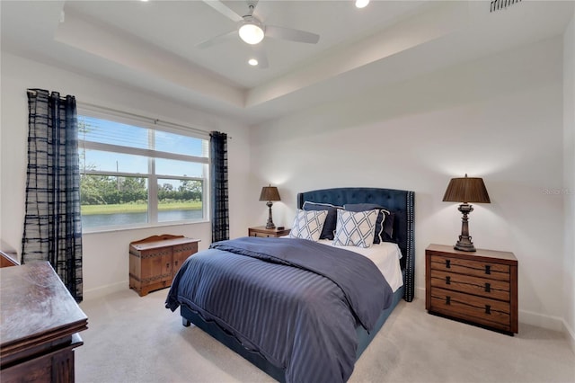 bedroom with light carpet, a raised ceiling, and ceiling fan