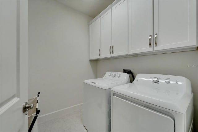 clothes washing area with cabinets and washing machine and clothes dryer