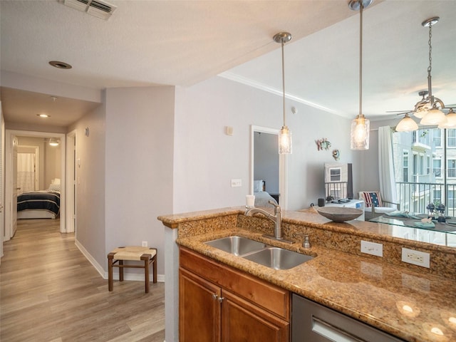 kitchen with sink, light hardwood / wood-style flooring, ceiling fan, light stone counters, and decorative light fixtures