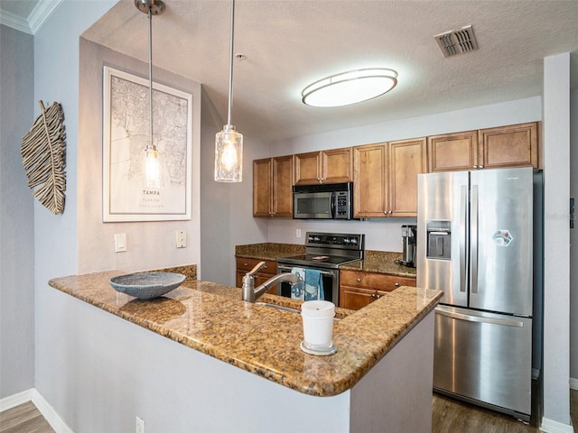 kitchen with pendant lighting, dark hardwood / wood-style flooring, light stone counters, kitchen peninsula, and stainless steel appliances