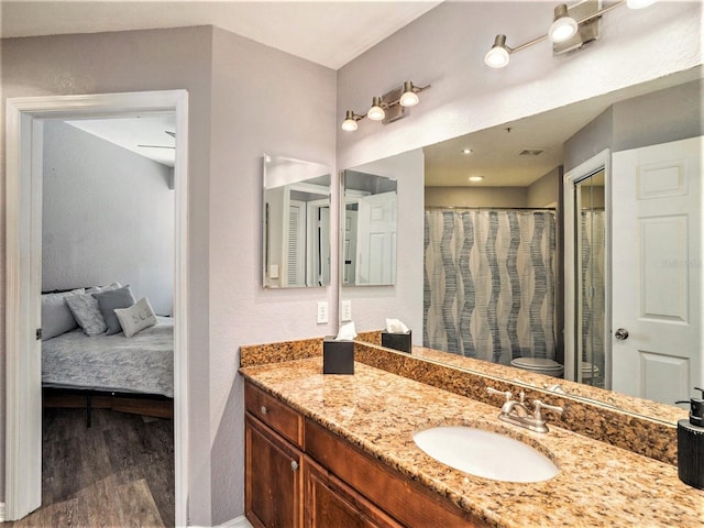 bathroom with hardwood / wood-style flooring, vanity, curtained shower, and toilet