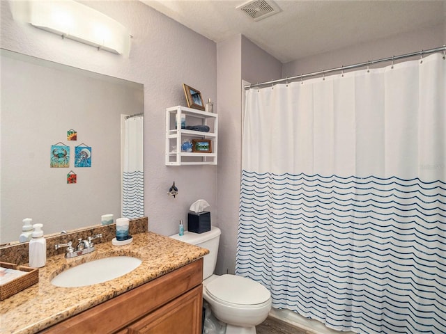 bathroom featuring vanity, a textured ceiling, and toilet