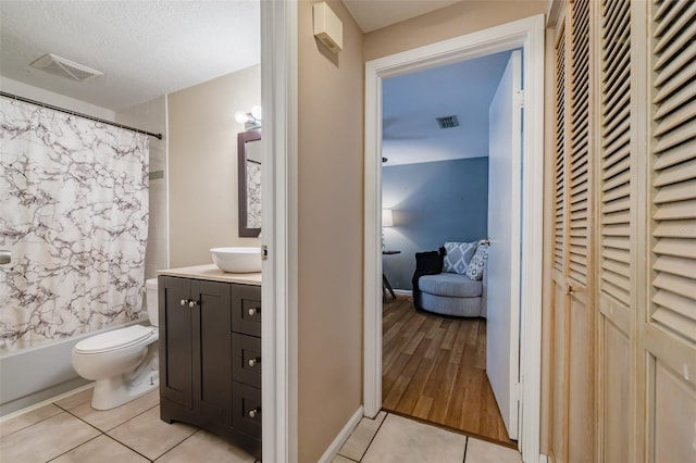 full bathroom featuring shower / tub combo, a textured ceiling, toilet, vanity, and tile patterned flooring